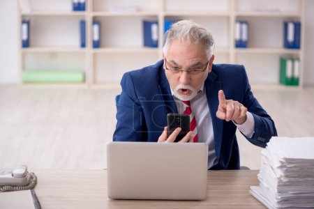 Téléchargez les photos : Old employee unhappy with excessive work at workplace - en image libre de droit