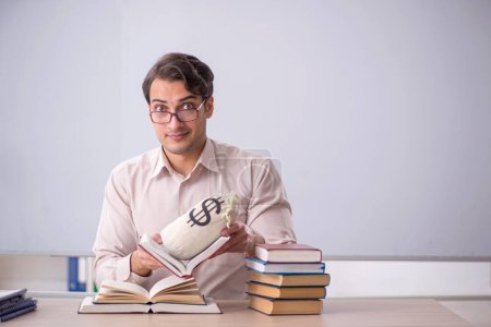 Photo for Young student holding moneybag in the classroom - Royalty Free Image