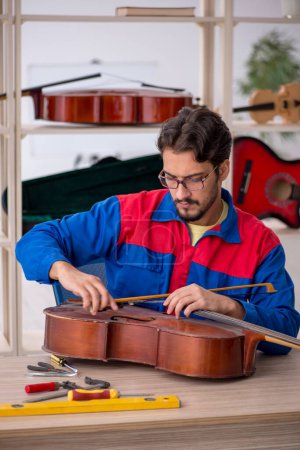 Foto de Joven reparando instrumentos musicales en interiores - Imagen libre de derechos