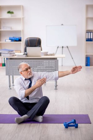 Téléchargez les photos : Ancien employé masculin faisant des exercices sportifs pendant la pause - en image libre de droit