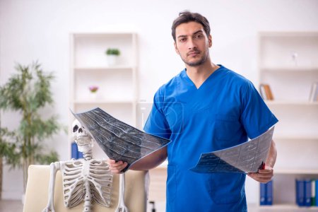 Téléchargez les photos : Jeune médecin radiologue et patient squelette à la clinique - en image libre de droit