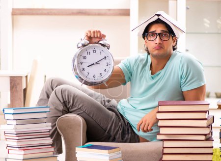 Téléchargez les photos : L'étudiant mâle avec de nombreux livres à la maison - en image libre de droit