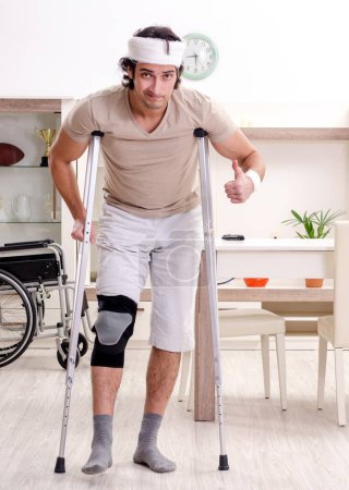 Téléchargez les photos : Le jeune homme blessé faisant des exercices à la maison - en image libre de droit