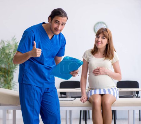 Foto de La mujer embarazada que visita al médico ginecólogo masculino - Imagen libre de derechos