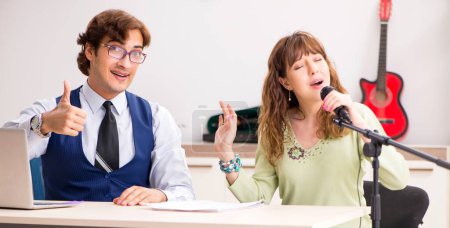 Photo for The young woman during music lesson with male teacher - Royalty Free Image