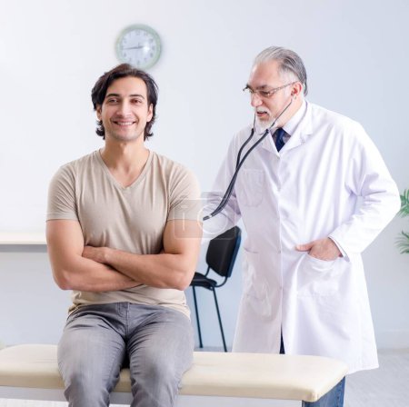 Téléchargez les photos : The young male patient visiting old doctor - en image libre de droit