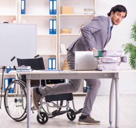 Téléchargez les photos : Le jeune et beau employé en fauteuil roulant au bureau - en image libre de droit