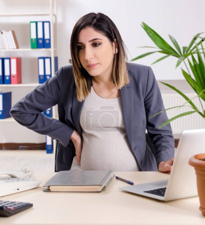 Photo for The young pregnant employee working in the office - Royalty Free Image