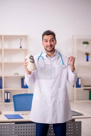 Photo for Young doctor holding moneybag in remuneration concept - Royalty Free Image