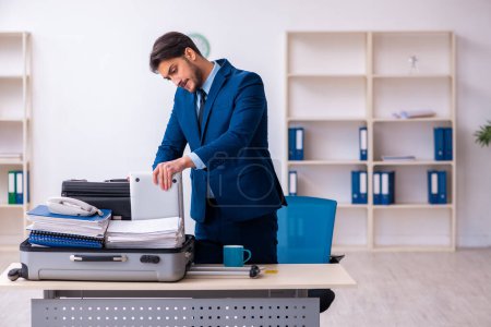 Photo for Young businessman employee preparing for business trip at workplace - Royalty Free Image