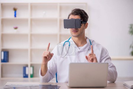 Foto de Joven médico masculino disfrutando de gafas virtuales en la clínica - Imagen libre de derechos