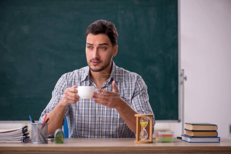 Téléchargez les photos : Young teacher drinking tea in the classroom - en image libre de droit