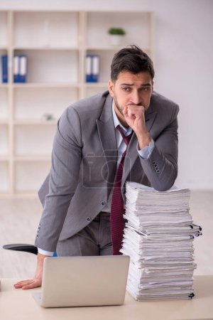Photo for Young employee and too much work at workplace - Royalty Free Image