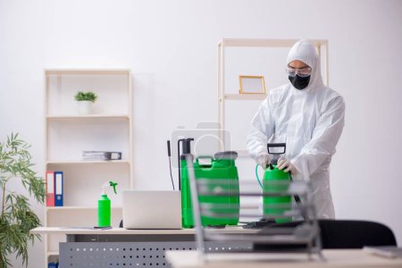 Photo for Young contractor disinfecting office during pandemic - Royalty Free Image