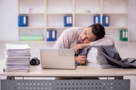 Photo for Young employee and too much work at workplace - Royalty Free Image