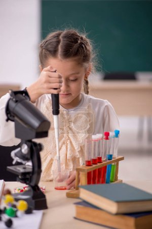 Téléchargez les photos : Little girl studying chemistry in the classroom - en image libre de droit