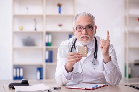 Foto de Viejo doctor sugiriendo pastillas en el hospital - Imagen libre de derechos