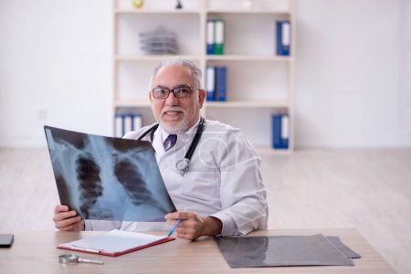Téléchargez les photos : Vieux médecin radiologue travaillant à la clinique - en image libre de droit