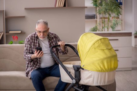 Photo for Old man looking after baby at home - Royalty Free Image