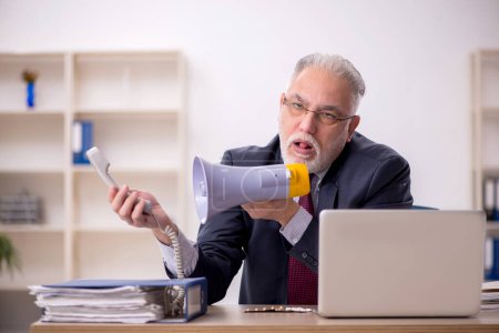 Foto de Viejo empleado de negocios sosteniendo el magáfono en la oficina - Imagen libre de derechos