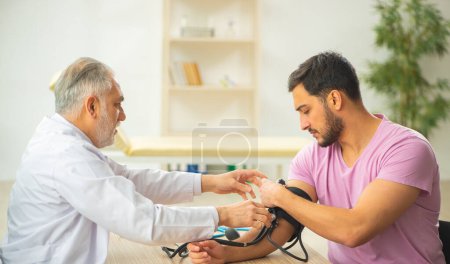 Photo for Old doctor measuring young patients blood pressure - Royalty Free Image