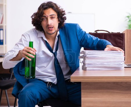 Téléchargez les photos : Le jeune employé ivre dans le bureau - en image libre de droit