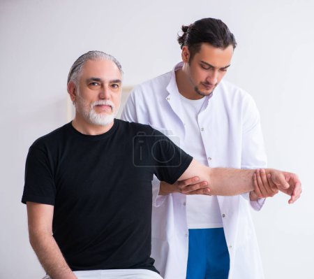 Photo for The old injured man visiting young doctor - Royalty Free Image