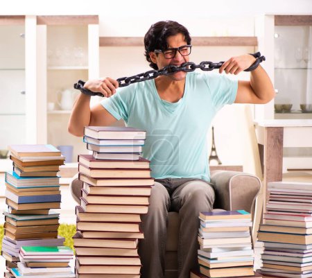 Foto de El estudiante masculino con muchos libros en casa - Imagen libre de derechos