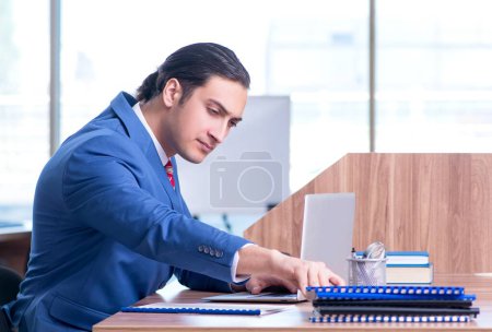 Téléchargez les photos : Le jeune homme d'affaires beau assis dans le bureau - en image libre de droit