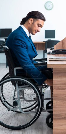 Téléchargez les photos : Le jeune employé masculin en fauteuil roulant - en image libre de droit