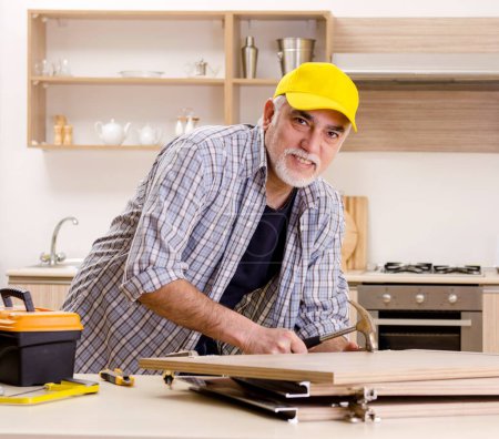 Photo for The aged contractor repairman working in the kitchen - Royalty Free Image