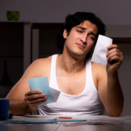 Photo for The young man calculating expences night at home - Royalty Free Image