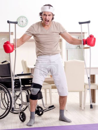 Photo for The injured young man doing exercises at home - Royalty Free Image
