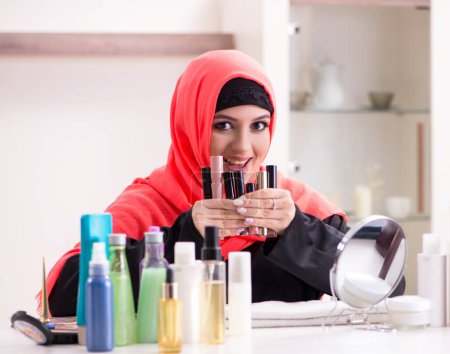 Photo for The beautiful woman in hijab applying make-up - Royalty Free Image