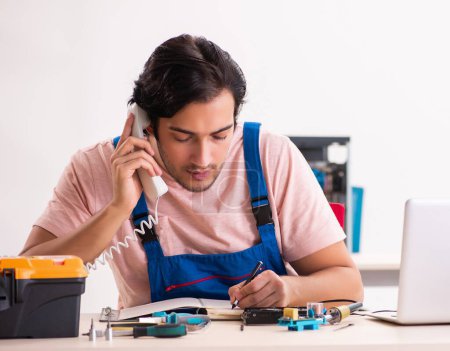 Téléchargez les photos : Le jeune entrepreneur masculin réparer l'ordinateur - en image libre de droit