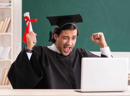 Téléchargez les photos : L'étudiant diplômé devant le tableau vert - en image libre de droit
