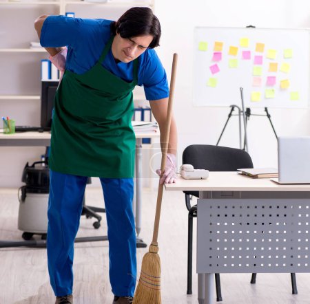 Téléchargez les photos : Le beau garçon nettoyeur professionnel travaillant dans le bureau - en image libre de droit