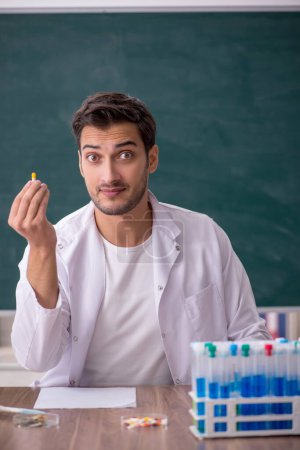 Téléchargez les photos : Young chemist in front of green board - en image libre de droit