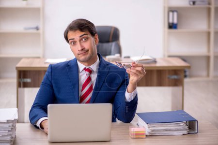 Photo for Young businessman employee and too much work in the office - Royalty Free Image
