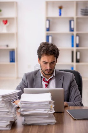 Photo for Young businessman employee unhappy with excessive work in the office - Royalty Free Image