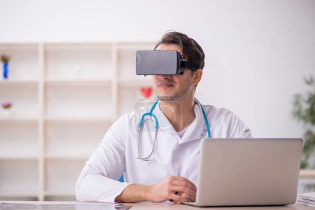 Foto de Joven médico masculino disfrutando de gafas virtuales en la clínica - Imagen libre de derechos