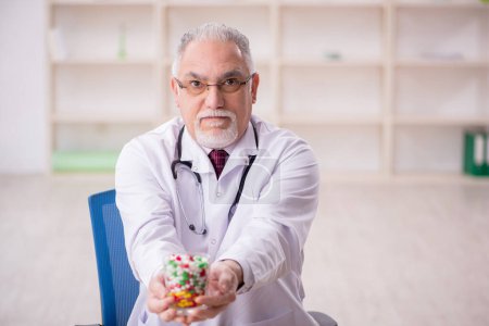 Foto de Viejo doctor sugiriendo pastillas en la clínica - Imagen libre de derechos