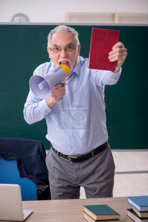Foto de Old teacher holding megaphone in the classroom - Imagen libre de derechos