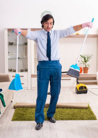 Téléchargez les photos : Le jeune homme d'affaires nettoie la maison - en image libre de droit
