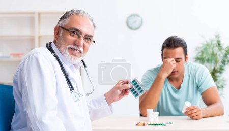 Photo for The young man visiting old male doctor - Royalty Free Image