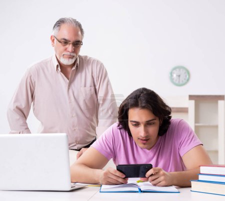 Foto de El viejo padre ayudando a su hijo en la preparación del examen - Imagen libre de derechos
