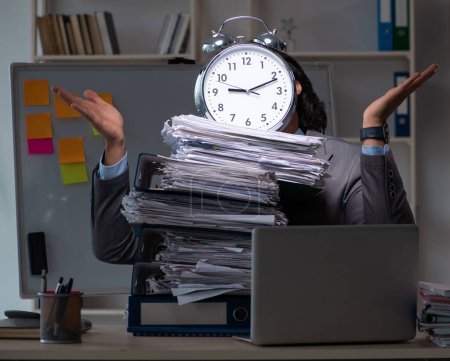 Foto de El joven empleado que trabaja hasta tarde en la oficina - Imagen libre de derechos