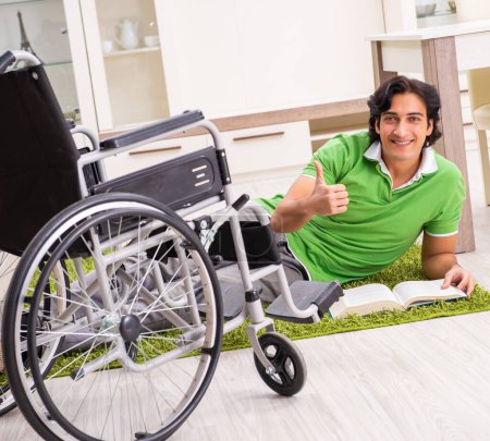 Téléchargez les photos : The young handsome man in wheelchair at home - en image libre de droit