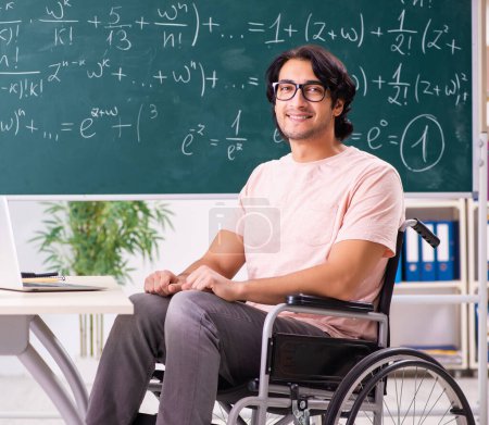 Téléchargez les photos : The young handsome man in wheelchair in front of chalkboard - en image libre de droit