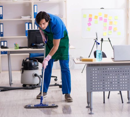 Téléchargez les photos : Le beau garçon nettoyeur professionnel travaillant dans le bureau - en image libre de droit